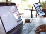 Bild på en öppen laptop och en person som håller i en telfon med ett instagram eller social media flöde uppe.