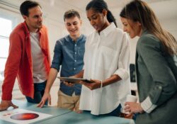 Marketing team analyzing data on tablet and printed reports in office meeting